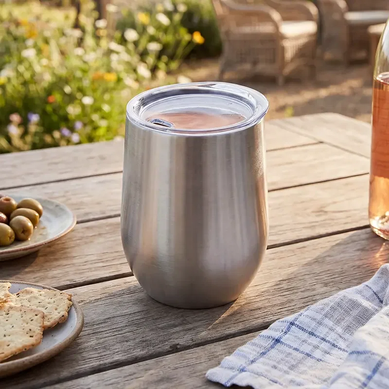 Vaso de acero inox con bebida, en una mesa al aire libre.